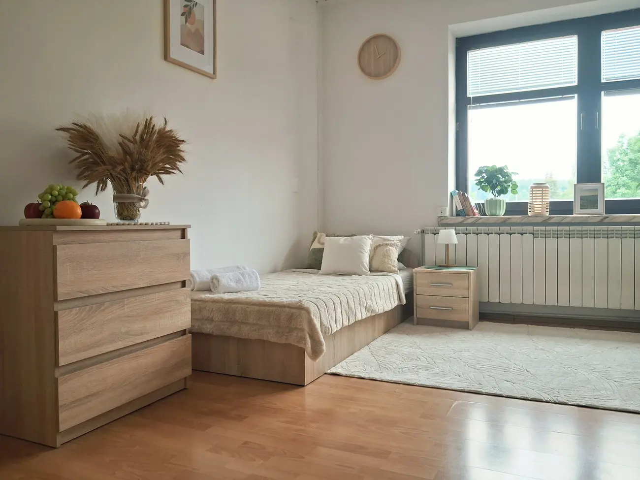 Sypialnia z łóżkiem przy oknie i komodą